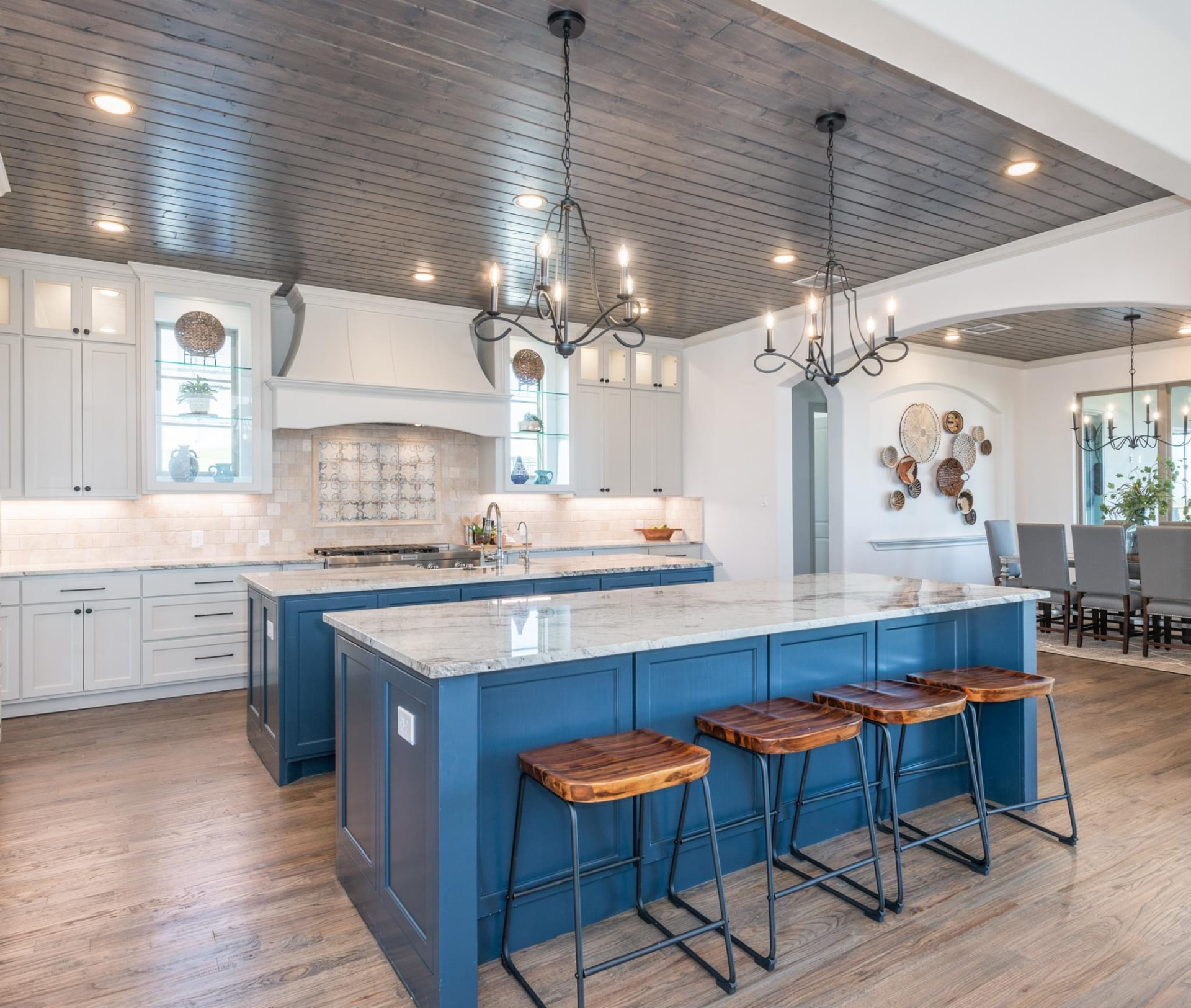 Open kitchen with white perimeter cabinetry and a blue painted island under a wood plank ceiling